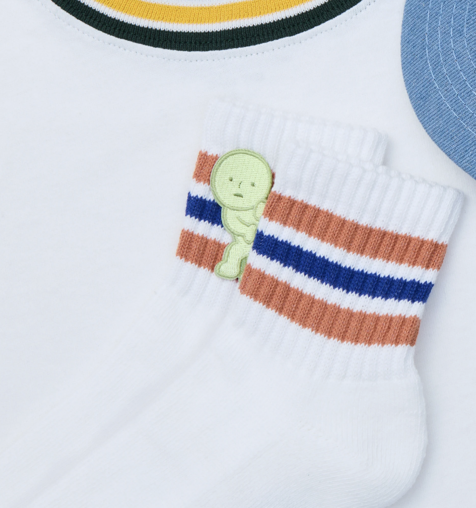 Smiski Peeking Embroidered Sticker series 1 peeking out from a pair of socks on a white background.