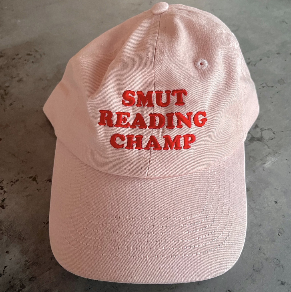 Pink ball cap with "Smut Reading Champ" embroidered in red on the front. 