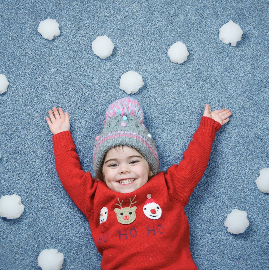 A kid lying on the floor surrounded with snoballs made with the Snoball Play Pack. 