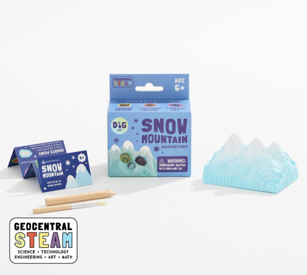 A blue box with graphics that read "Snow Mountain Adventure" and a picture of the plaster mountain covered with snow where the treasures are to be found. Set beside the box is the miniature mountain made from plaster, the wooden tools used to excavate the treasures and the instruction booklet. 