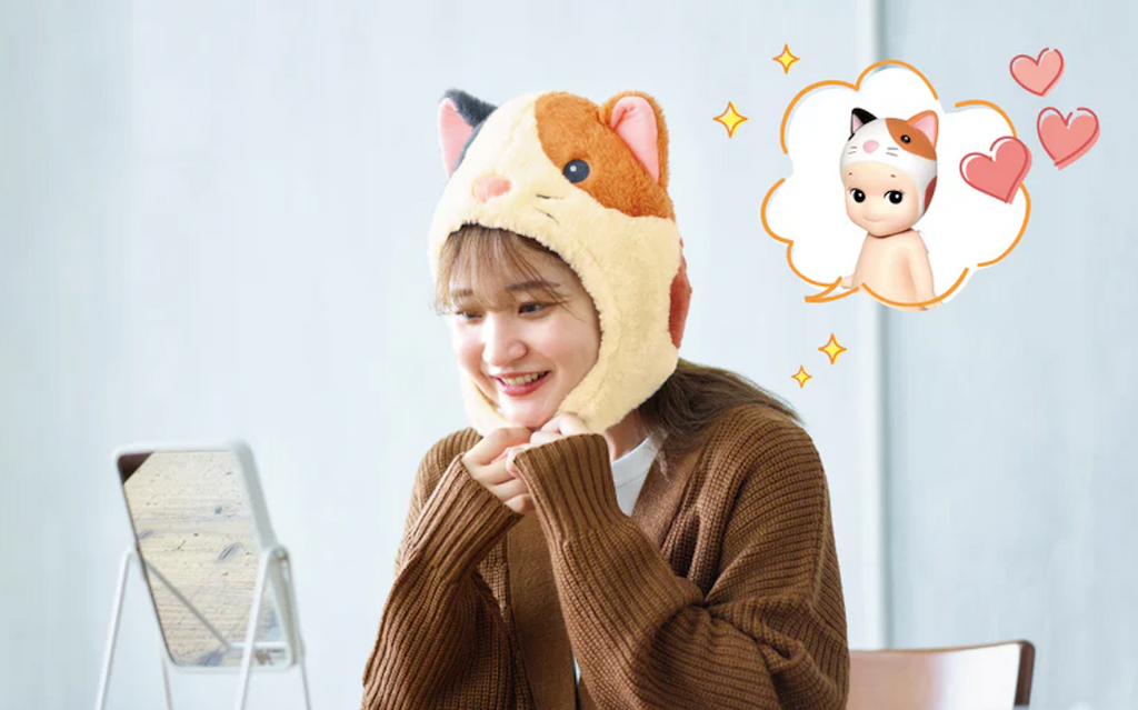 Someone wearing the Calico Cat Sonny Angel Costume plush hat and looking in a mirror with thoughts of the matching Sonny Angel Calico Cat figurine. 