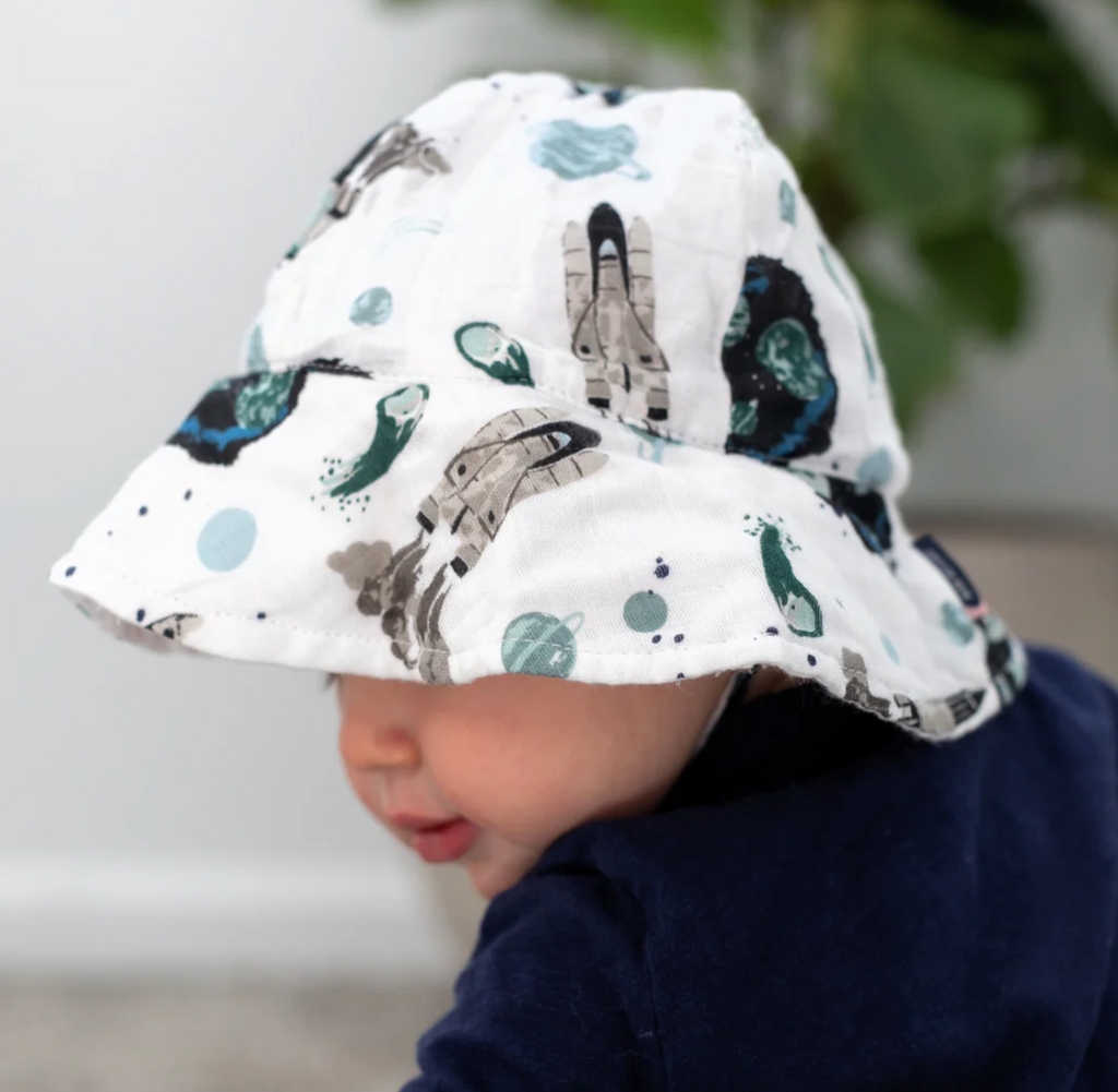 A baby wearing the Space Muslin sun hat, the wide brim is covering his face.