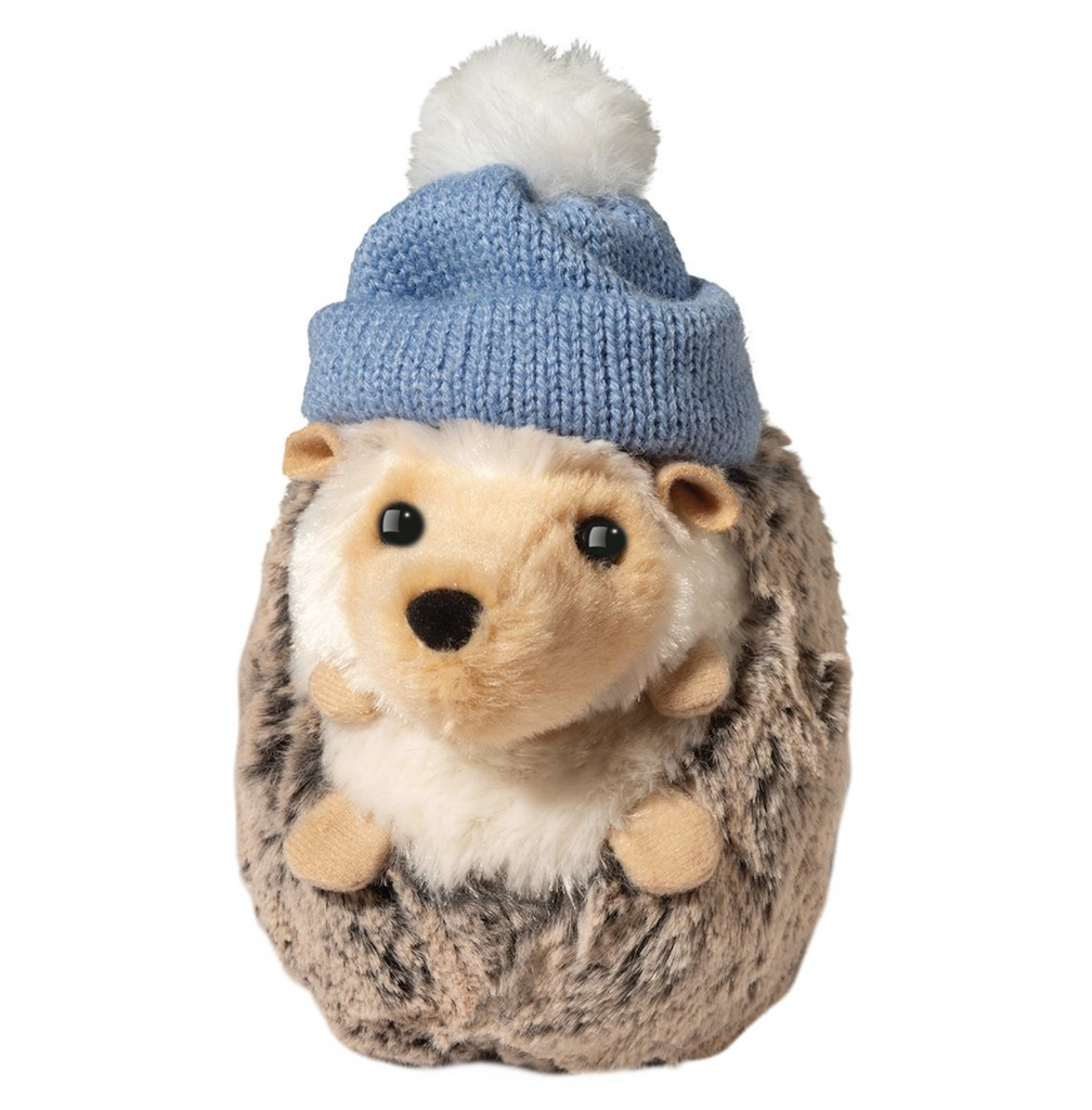 Hedgehog stuffed animal wearing a winter hat that is light blue with a white pom pom. 