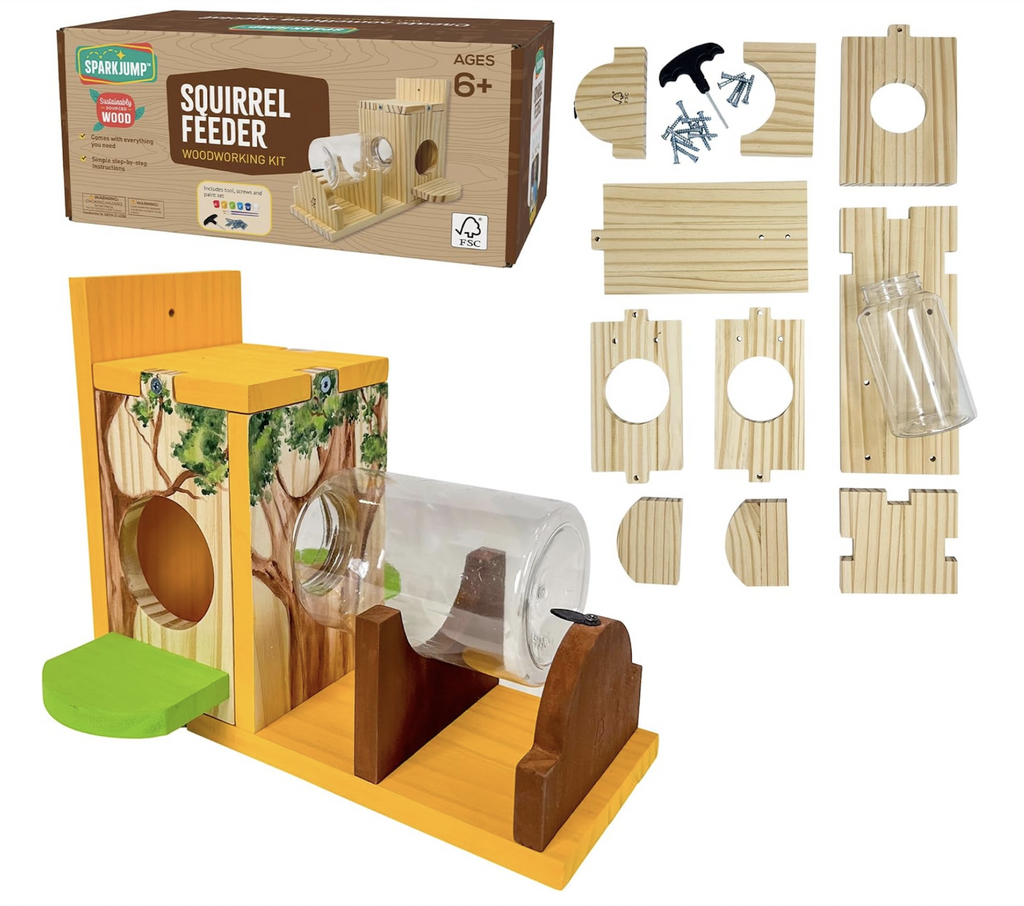 The Squirrel Feeder Woodworking kit completely built and painted in the foreground with all the pieces included set to the side and the box it all comes packaged in at the top left corner. 