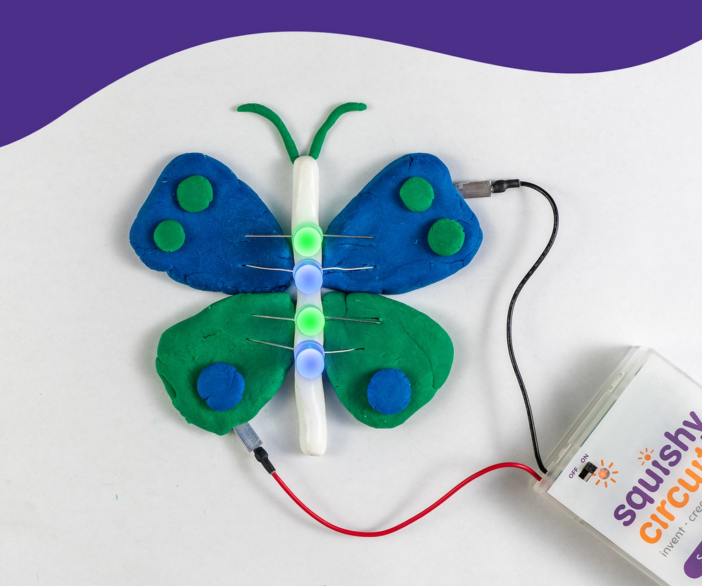 Blue and green butterfly made with the dough from the Squishy Circuits kit, connected to the battery pack and lit up. 