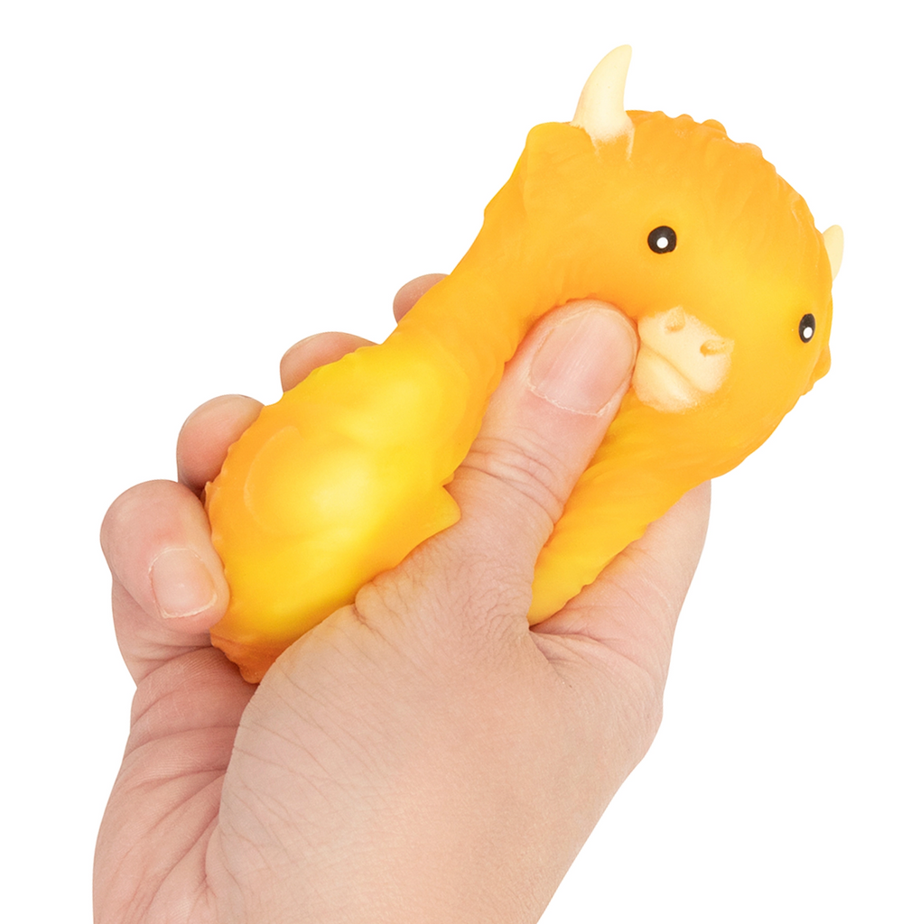 Yellow Squishy Rainbow Highland Cow squishy toy being squeezed by a hand. 
