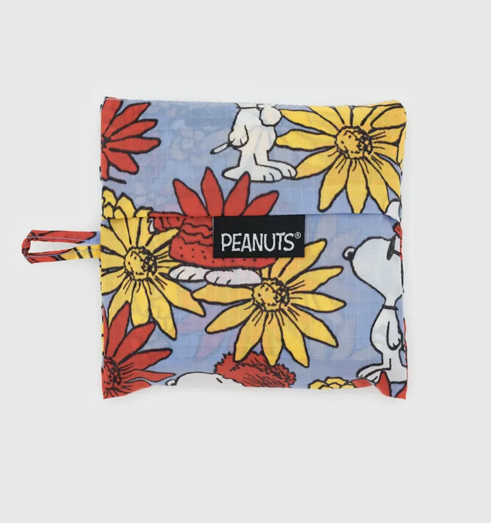 A standard sized Baggu bag folded flat into the pouch it comes in with the Floral Snoopy pattern printed on it. 