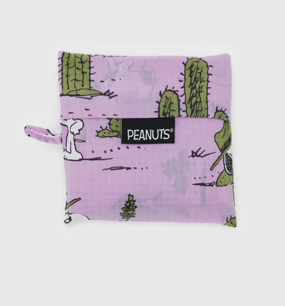 The standard Baggu folded and stored flat in the included pouch with the Pink Spike pattern which has a lilac background with Snoopy wearing a park ranger hat standing amongst cactus. 