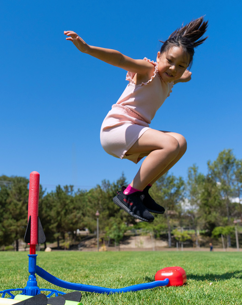 Action shot of a kid in the air about to land on the launch pad sending the foam Stomp Rocket into the air. 