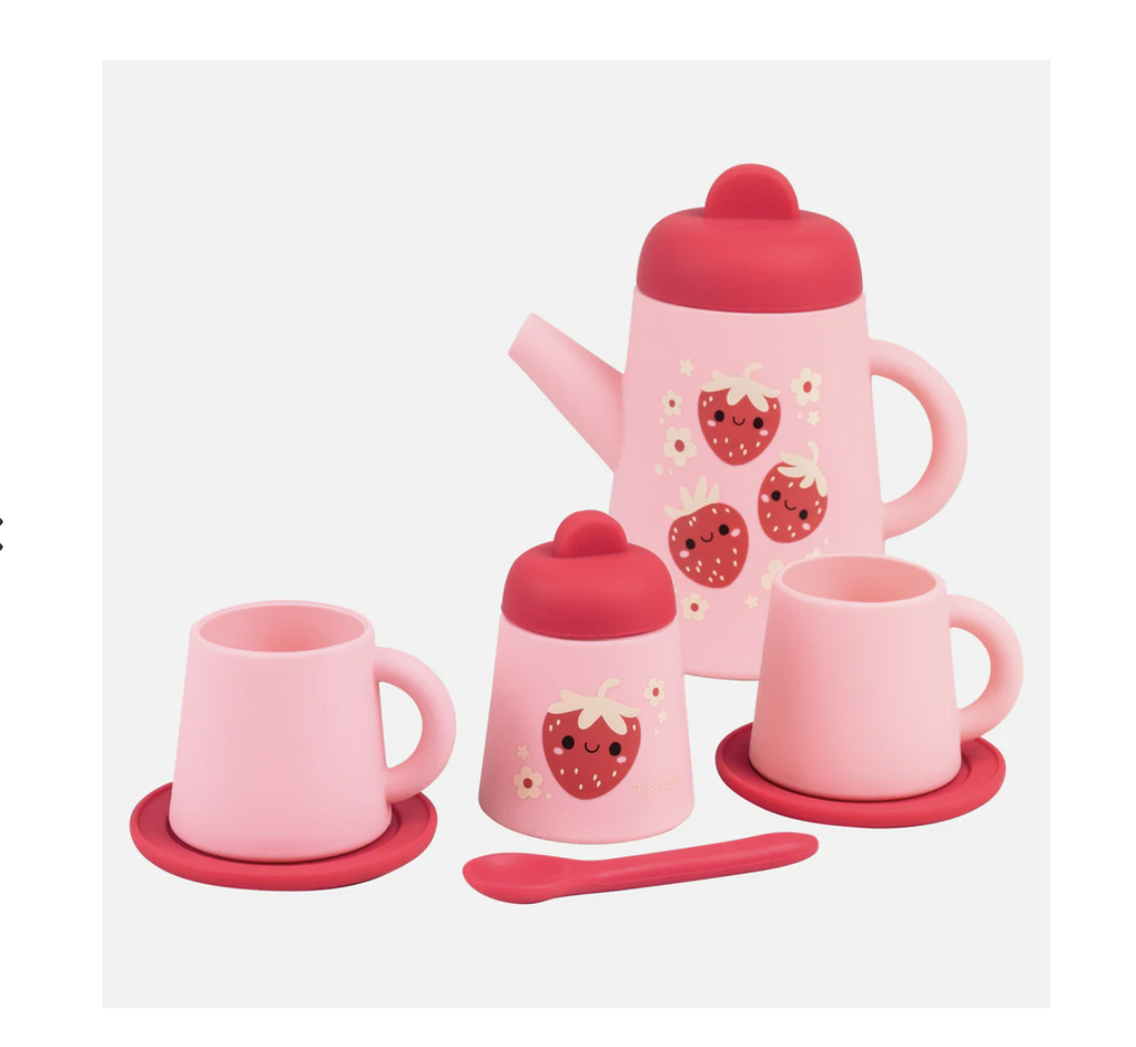 Strawberry patch silicone tea set includes a pink teapot with a dark pink lid, 2 pink cups with dark pink saucers, a dark pink spoon, and a pink sugar bowl with a dark pink lid. Both the sugar bowl and teapot are decorated with smiling strawberries.