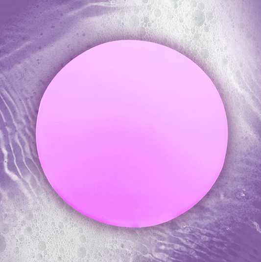 The StressLess BAth Light floating in water glowing with a purplish pink light. 
