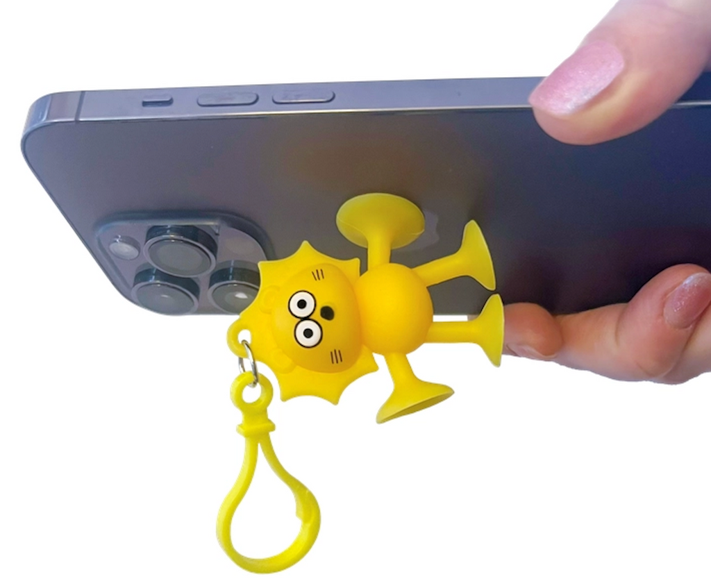 A yellow, lion shaped Suction Cup Cuitez attached to the back of a phone. 
