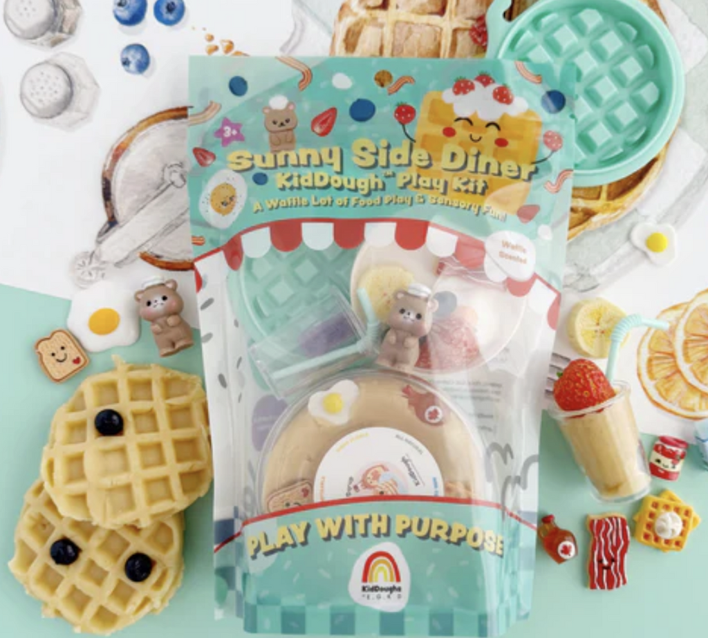 The Sunny Side Diner KidDough Play Kit bagged in a colorful bag that has a clear panel that shows the container of dough, waffle molding piece and figurines that are included in the kit. 