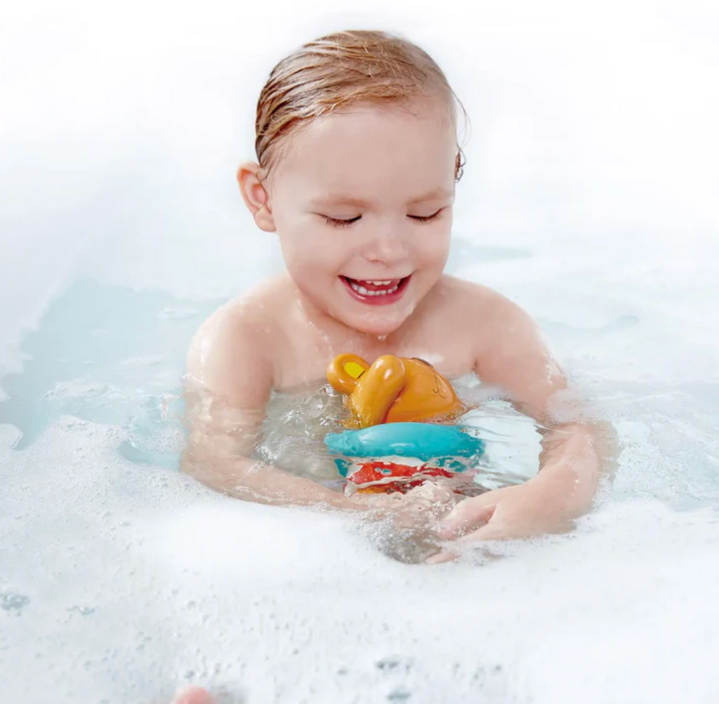 Child playing with bath toys in a bathtub filled with bubbles