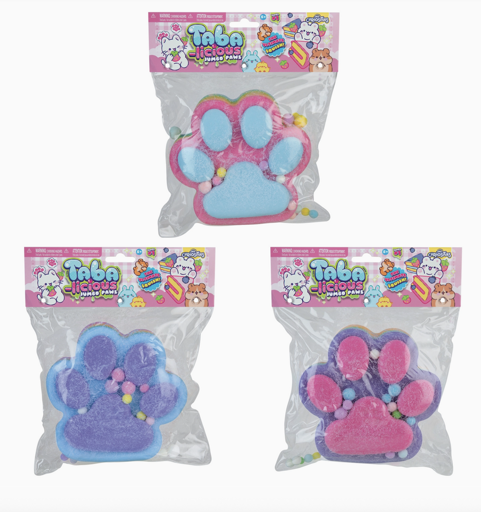 Three different colors of the Taba-Licious Jumbo Paws packaged in clear plastic packaging with pink headers. There is a a pink paw with light blue paw pads, a blue paw with purple paw pads, and a purple paw with pink paw pads. 