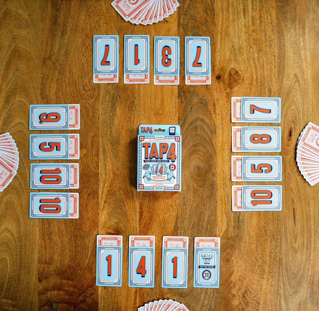 Card game 'Tap 4' on a wooden table with cards laid out.