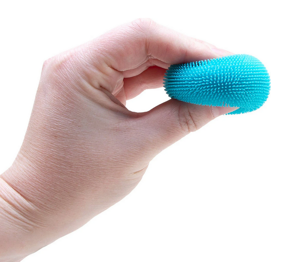 Hand squeezing a blue textured Teenie Needoh Fuzz Ball. 