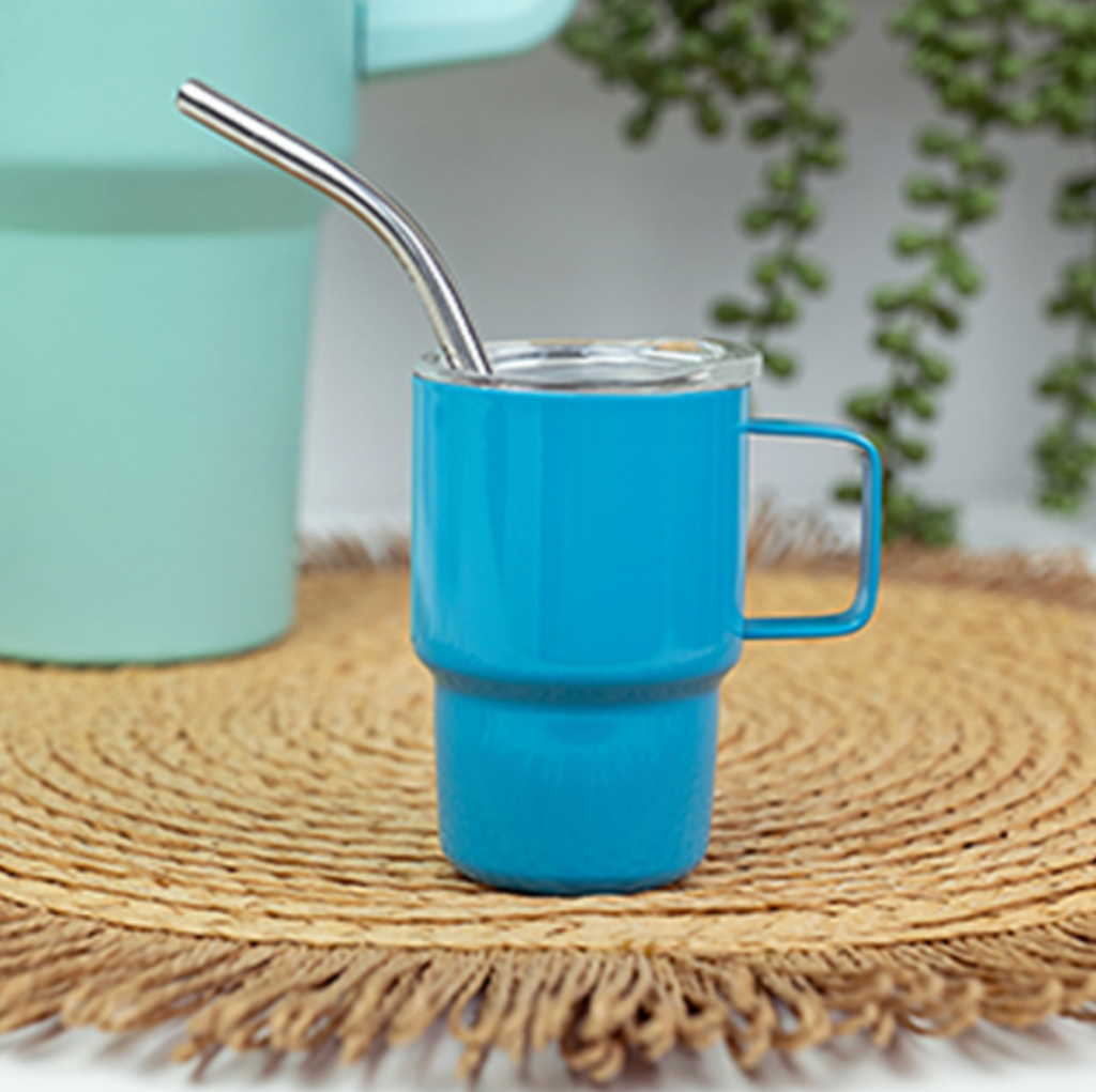 Close up picture of the mini travel mug with metal straw resting on a table. 