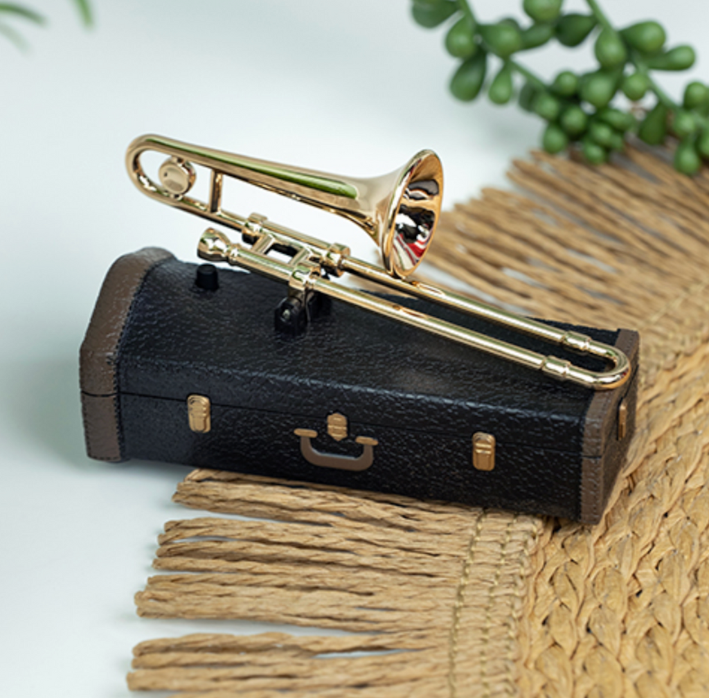 Teeny Town Womp Womp Trombone miniature noisemaker sitting atop it's black case on a table. 