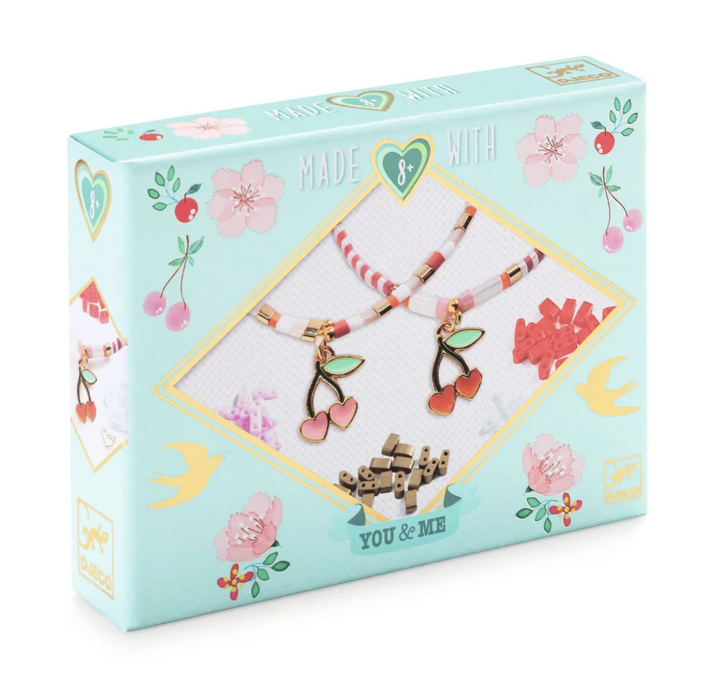 Pale green box with illustrations of cherries, and flowers along with pictures of bracelets made using the Tila and Cherries Beads and Jewelry Kit. 