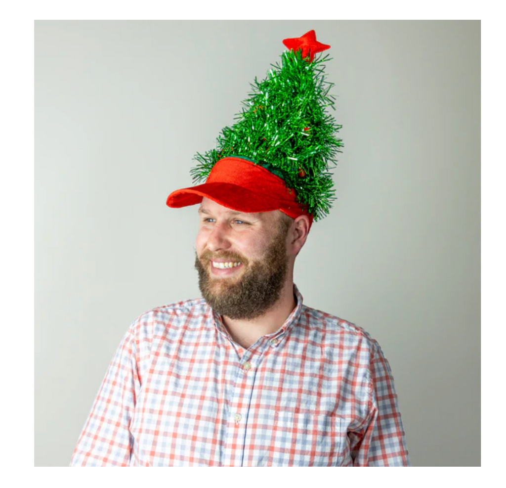 Person wearing a red visor with a green tinsel Christmas tree on top against a plain background