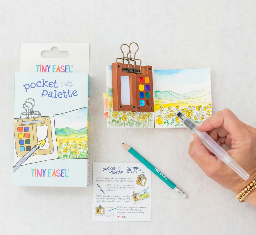 The box that holds the Pocket Palette, the sketchbook with the mini watercolor palette attached, a pencil and the refillable watercolor brush which are all included in the Pocket Palette from Tiny Easel. 