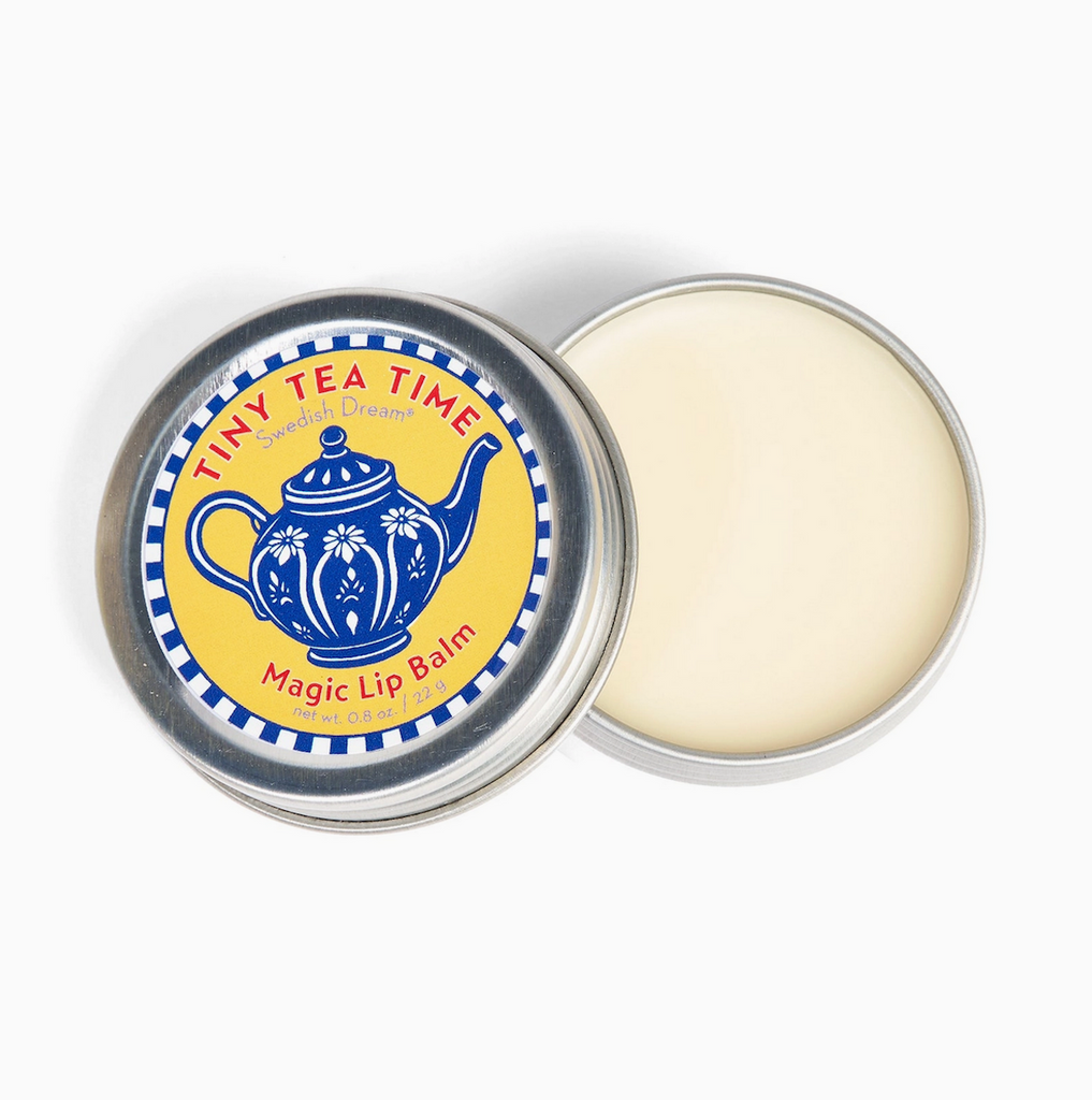 Lip balm in a tin with 'Tiny Tea Time' label open with the lid sitting to the side. 