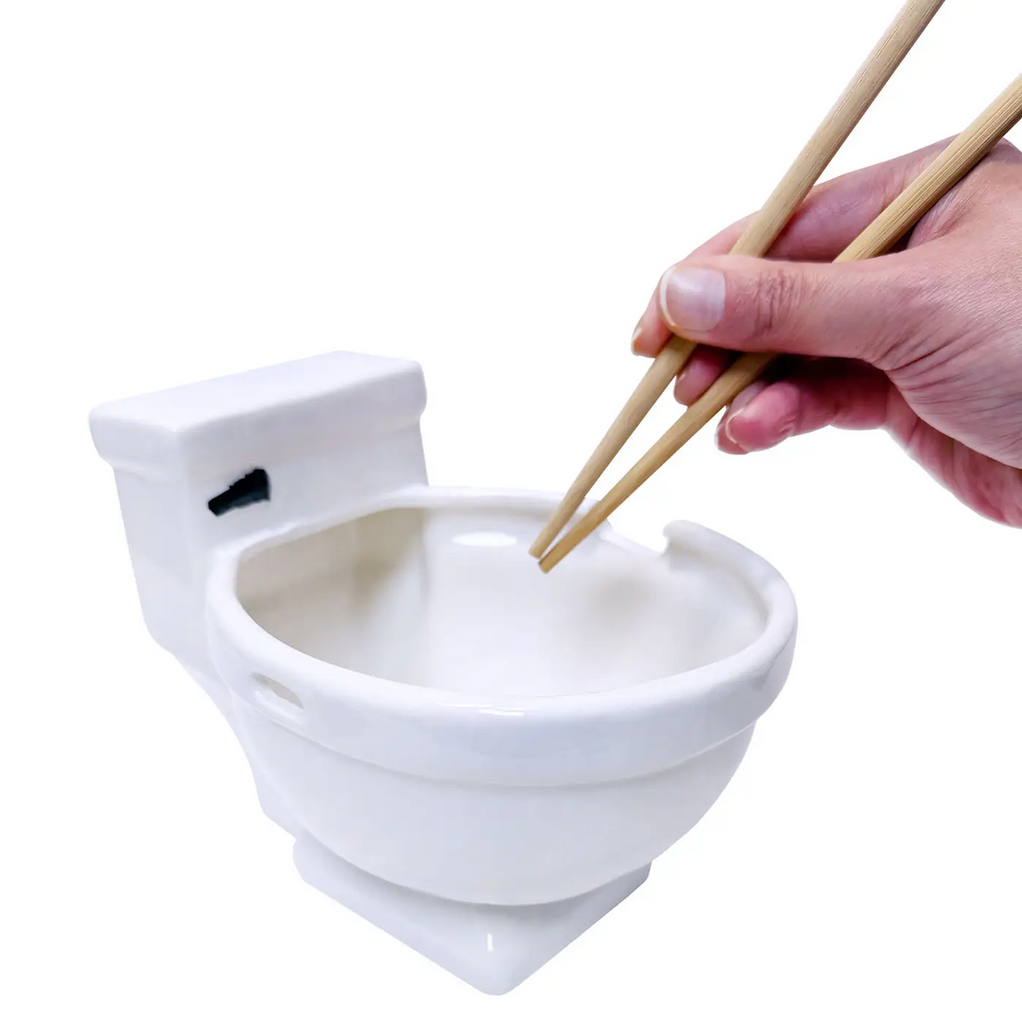 White ceramic bowl shaped like a toilet with a hand using chopsticks