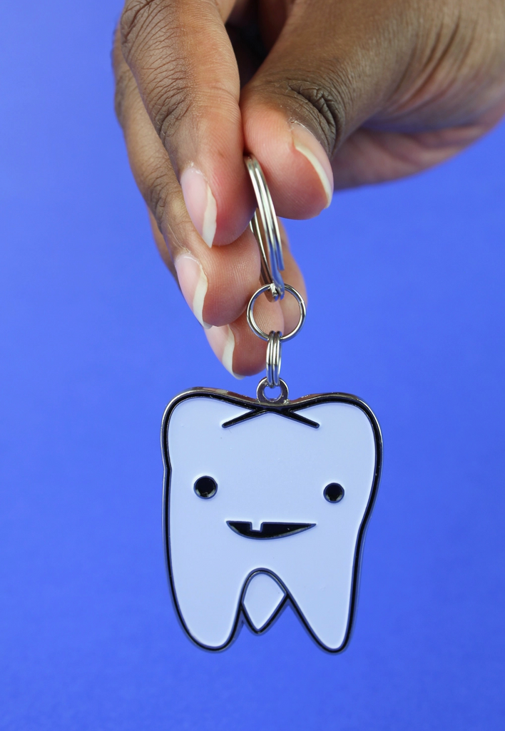 Enamel tooth keychain being held by the keyring.