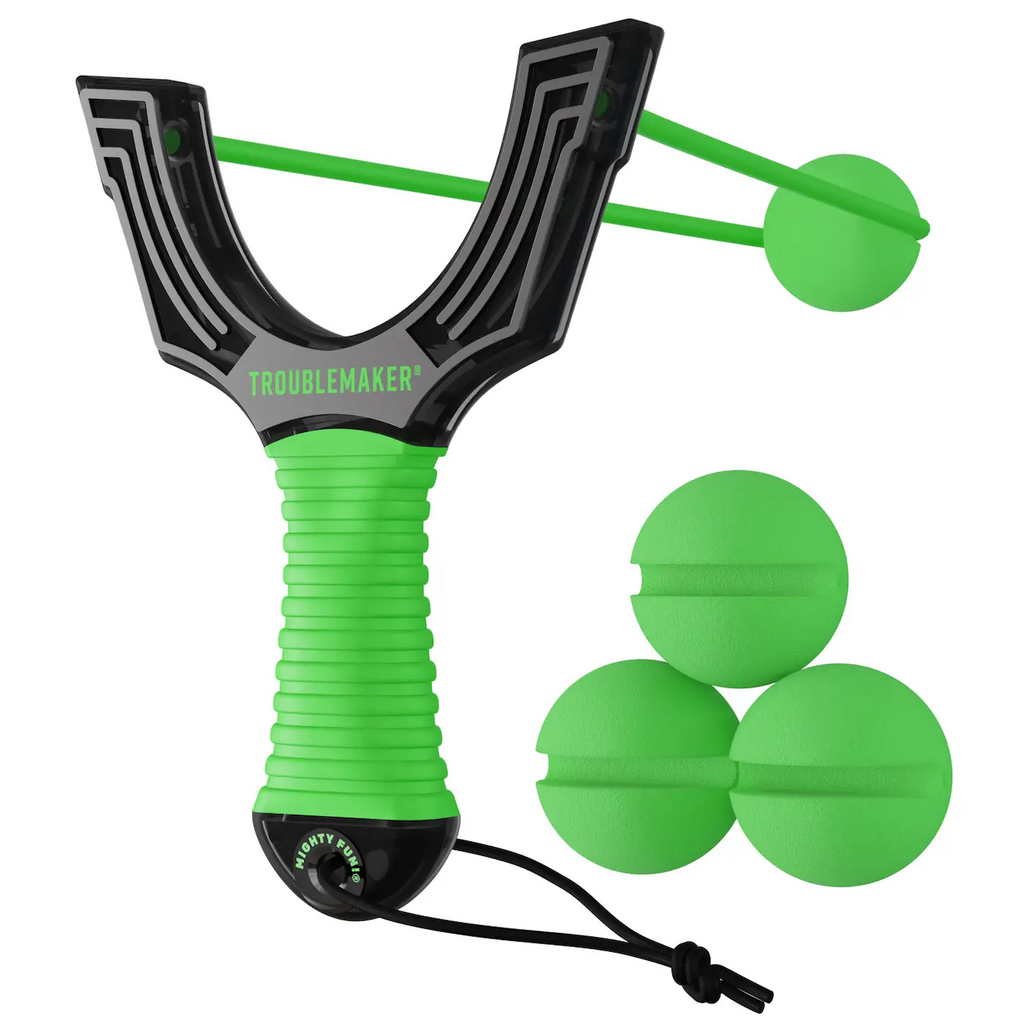 Trouble Maker Slingshot with black transparent plastic and a green soft gripped handle. Thre green foam balls are stacked to the side and one is loaded in the sling. 