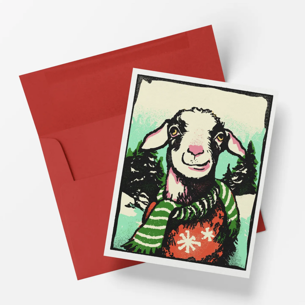 Holiday card features a goat in a sweater and scarf in a snowy backdrop.