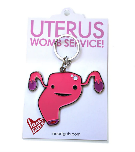 Pink enamel uterus shaped keychain on white backing card.