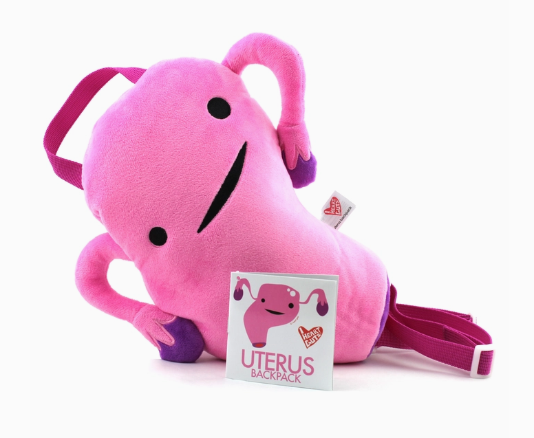 Bright pink plush backpack shaped like a uterus with dark pink shoulder straps.
