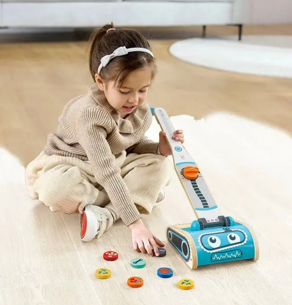 A young child playing with the toy vacuum.