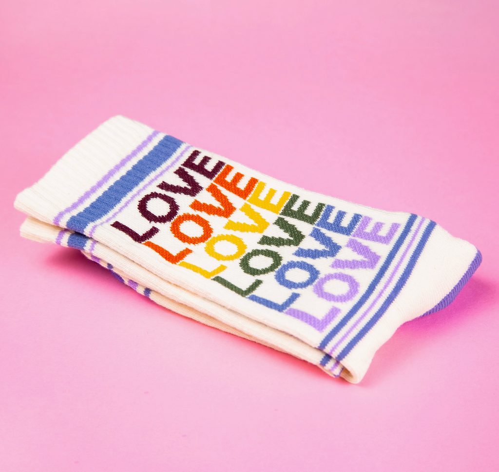 White tube socks with light blue and purple stripes and "Love" in repeated rainbow colored letters. 