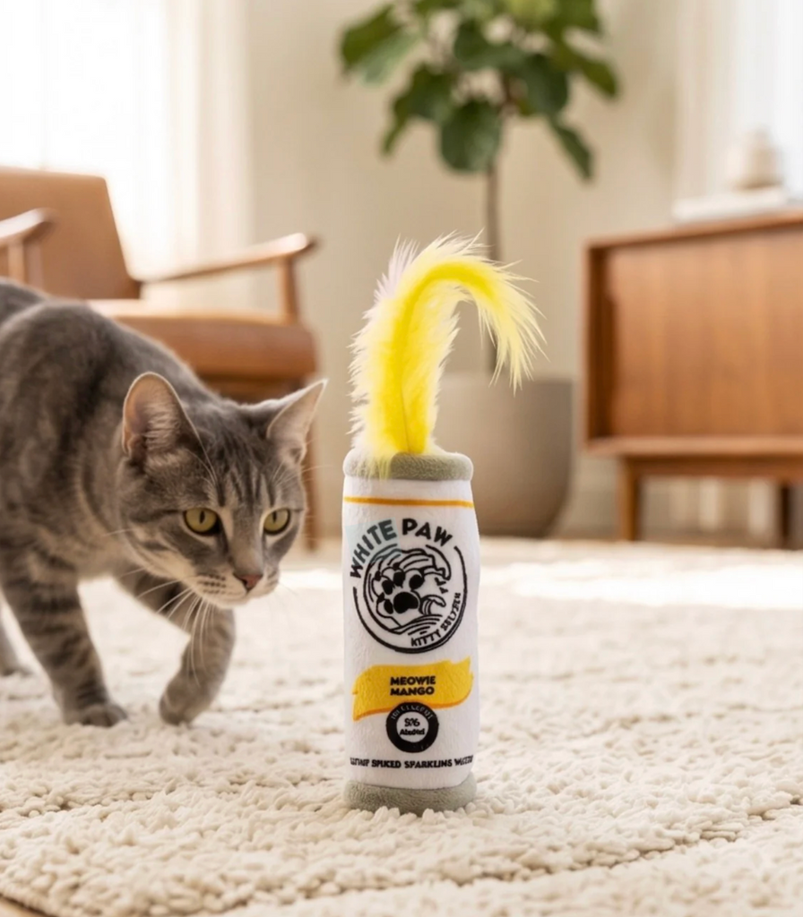 A gray tabby cat sneaking up on the Meowie Mango White Paw catnip toy.