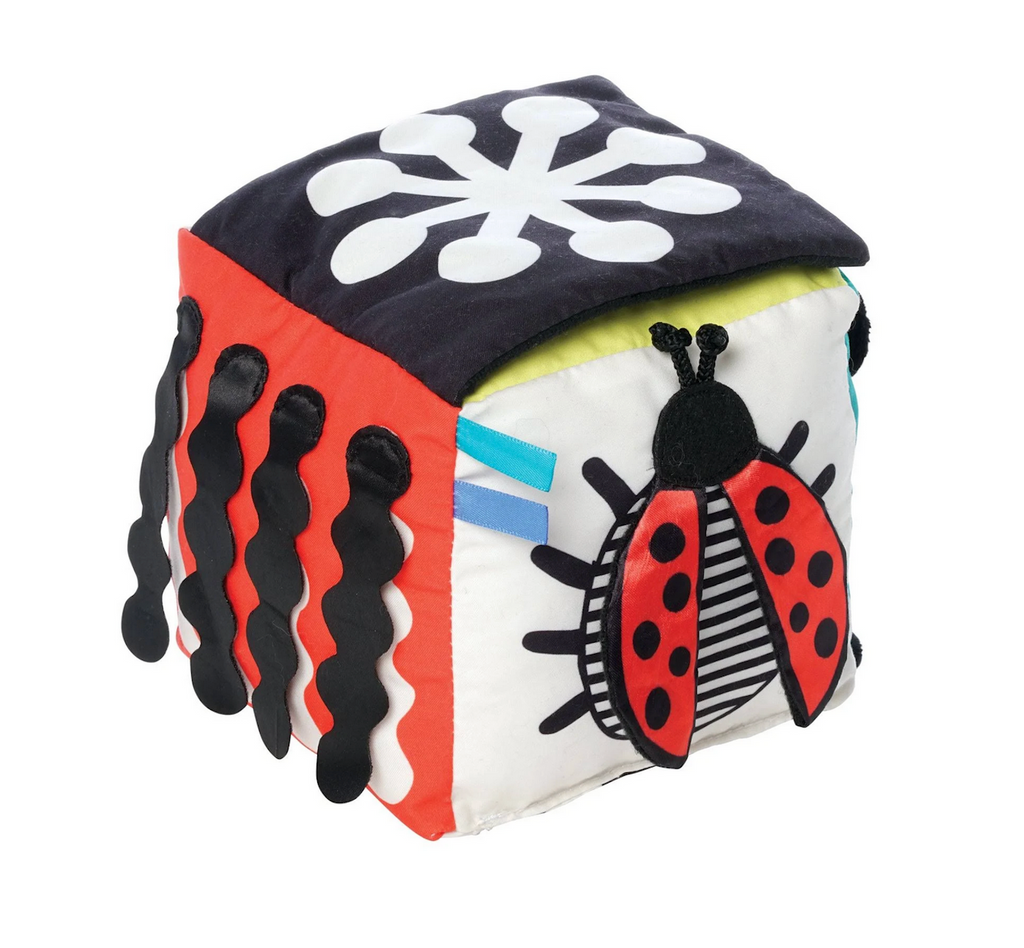 A view of three sides of the Wimmer Discovery Cube with a black and white contrast shape, textured ribbons that lift up, and a lady bug with crinkly wings, and high contrast body. 