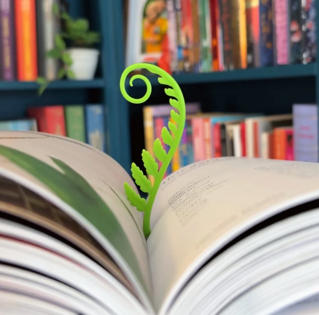 One of the two Woodland Sprouts fern shaped bookmarks keeping place int he center of a book. 
