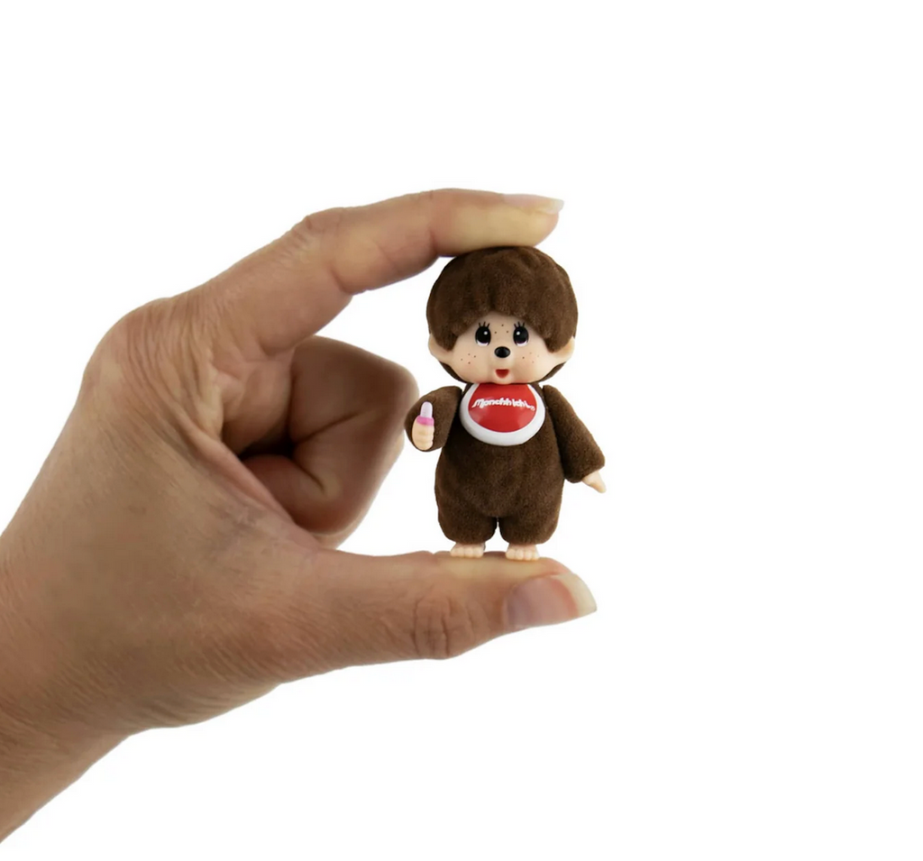 World's Smallest Monchhichi plush toy held between a thumb and pointer finger to show how tiny it is. 