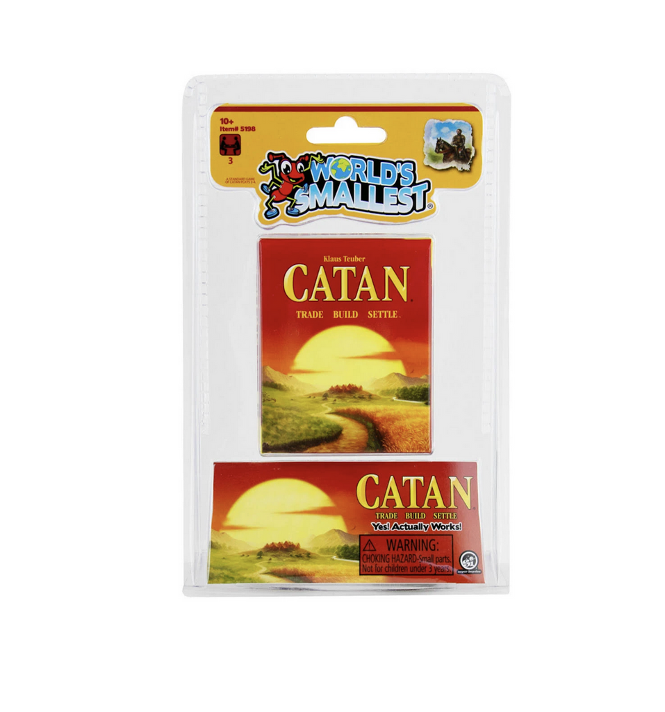 World's Smallest Catan game box in a clear plastic hangable package. The miniature version looks exactly like the original with an illustrated scene depicting the village built while playing the game. 