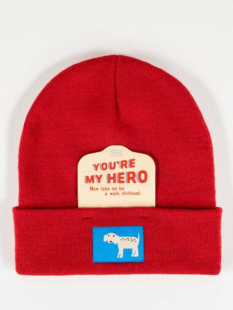 Red beanie with white dog on a blue tag embroidered on the front. Also has the removeable cardboard tag that reads You're My Hero, Now Take Me For A Walk Shithead. 