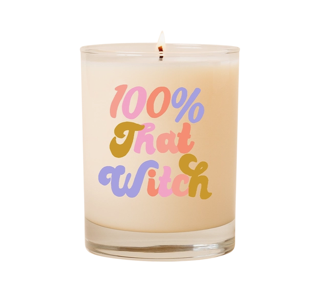 Clear rocks glass candle with !00% That Witch written on it in multicolored letters. 