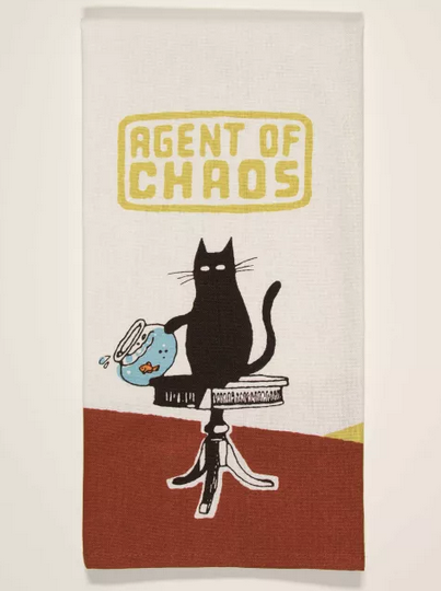 Folded dishtowel with illustration of a black cat on a table knocking off a fishbowl. It reads " Agent of Chaos"