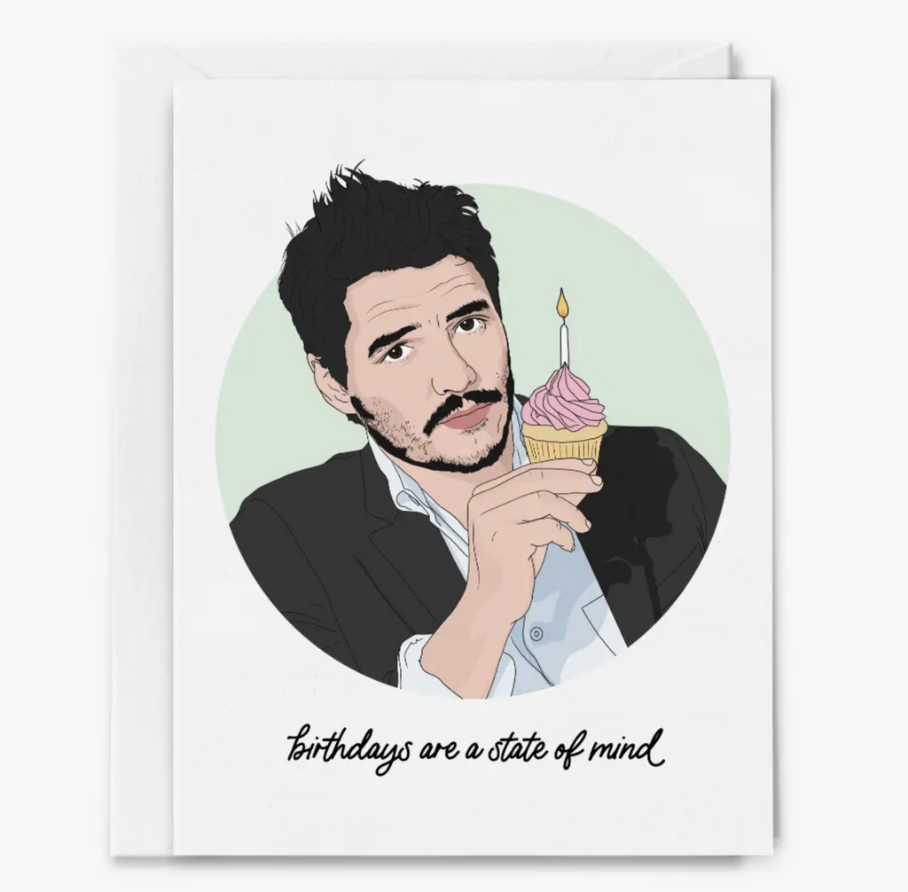 White greeting card with illustration of Pedro Pascal holding a cupcake with a candle that reads "Birthdays are a state of mind"