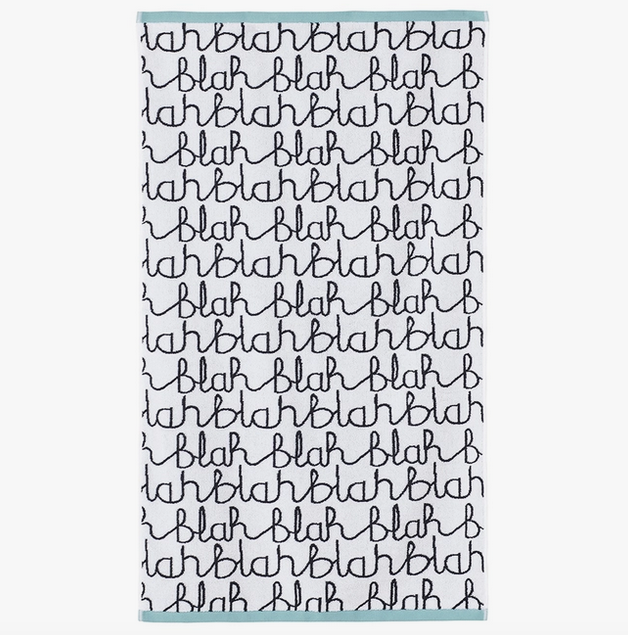 Blah, blah, blah bath towel by Donna Wilson. Towel is white with black letters and teal edges. 