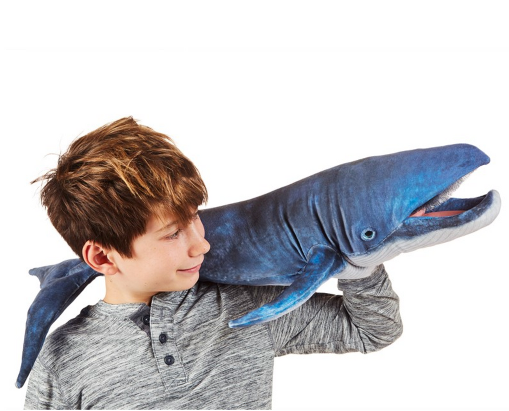 Child playing with blue whale puppet- across their shoulders to their hand.