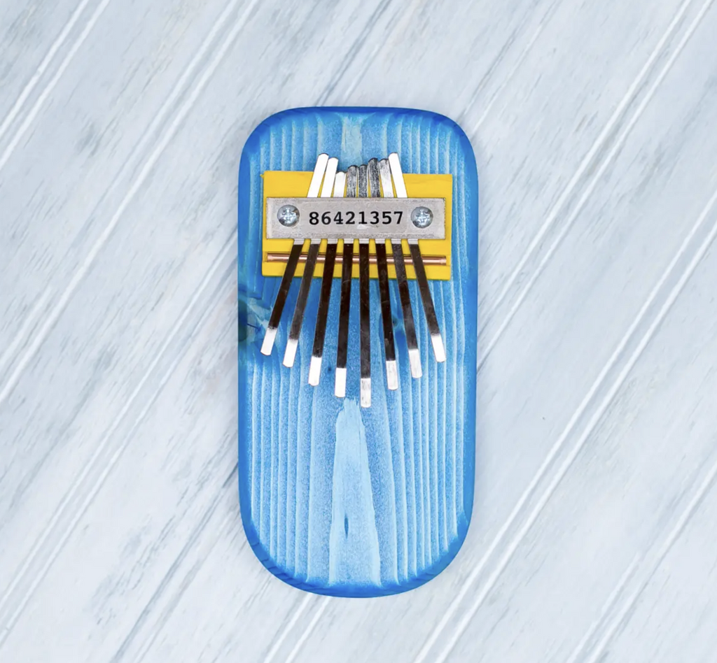 Pine Thumb Piano in blue on a grey background. 