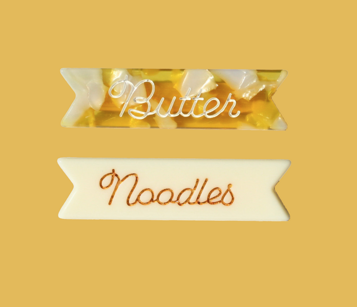Set of hairclips. One reads Butter, the other noodle.