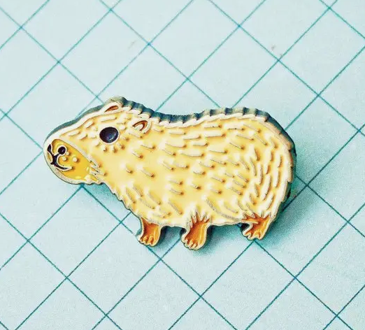 Capybara Enamel Pin. Made of iron with a brass colored finish and four colors of enamel, this pin measures approximately 1" wide and features butterfly clasps for easy closure.