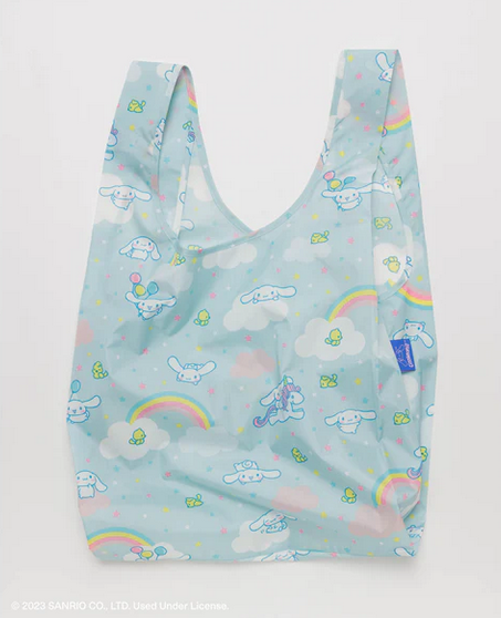 The Cinnamoroll standard baggu out of it's pouch lying on  flat surface. The pattern is light blue with Cinnamoroll, rainbows, and pink and blue stars. 